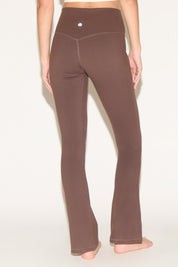 A person wearing brown yoga pants on a light background.