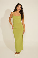 A model wearing a green sleeveless halter backless tie back side slit maxi dress with a cowl neckline.