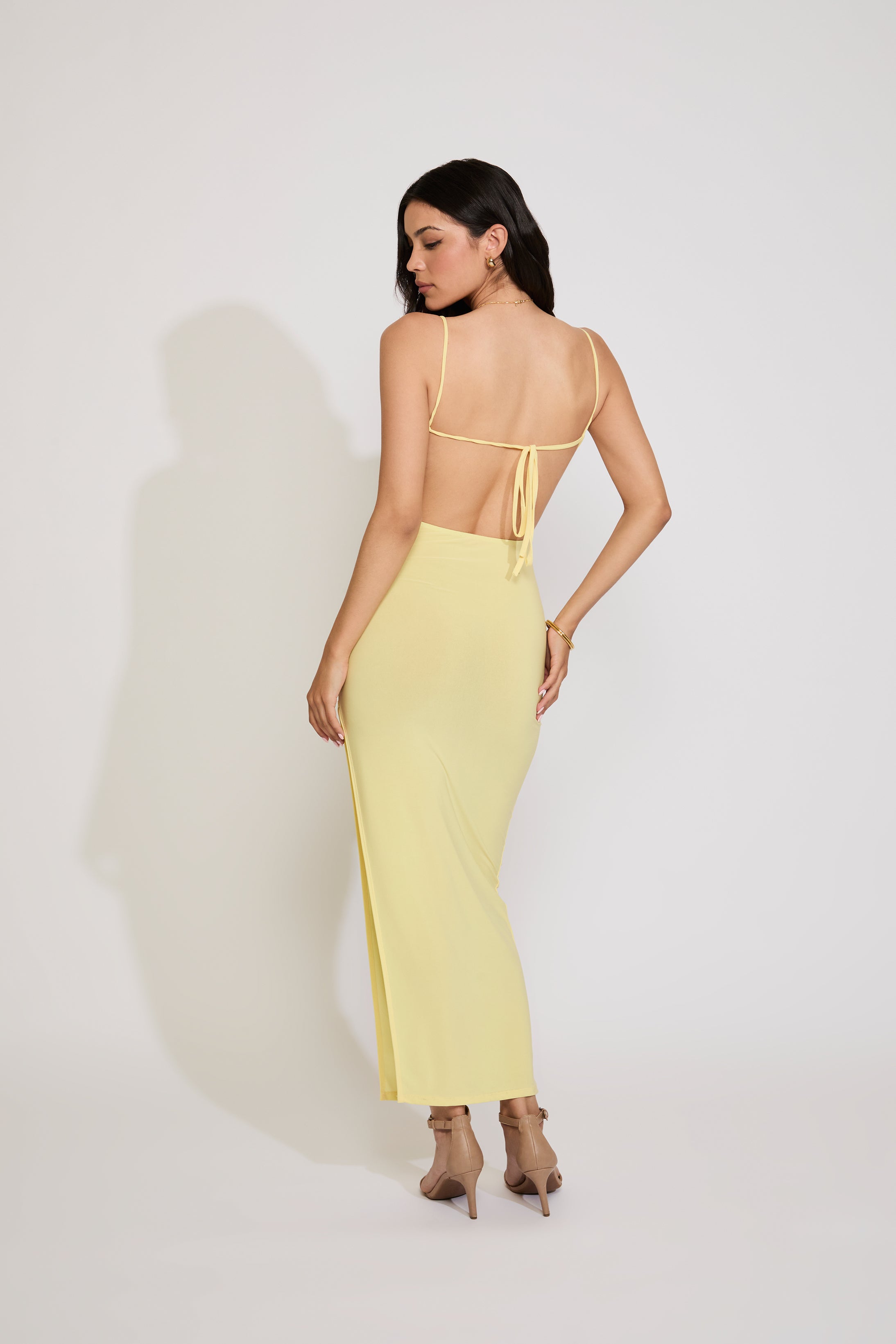 Woman wearing a yellow dress with thin straps on a white background