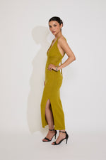 Woman wearing a mustard yellow dress with a slit on a white background