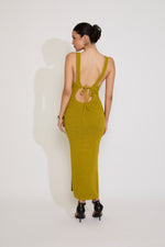 Woman wearing a green dress with cut-out back on a white background