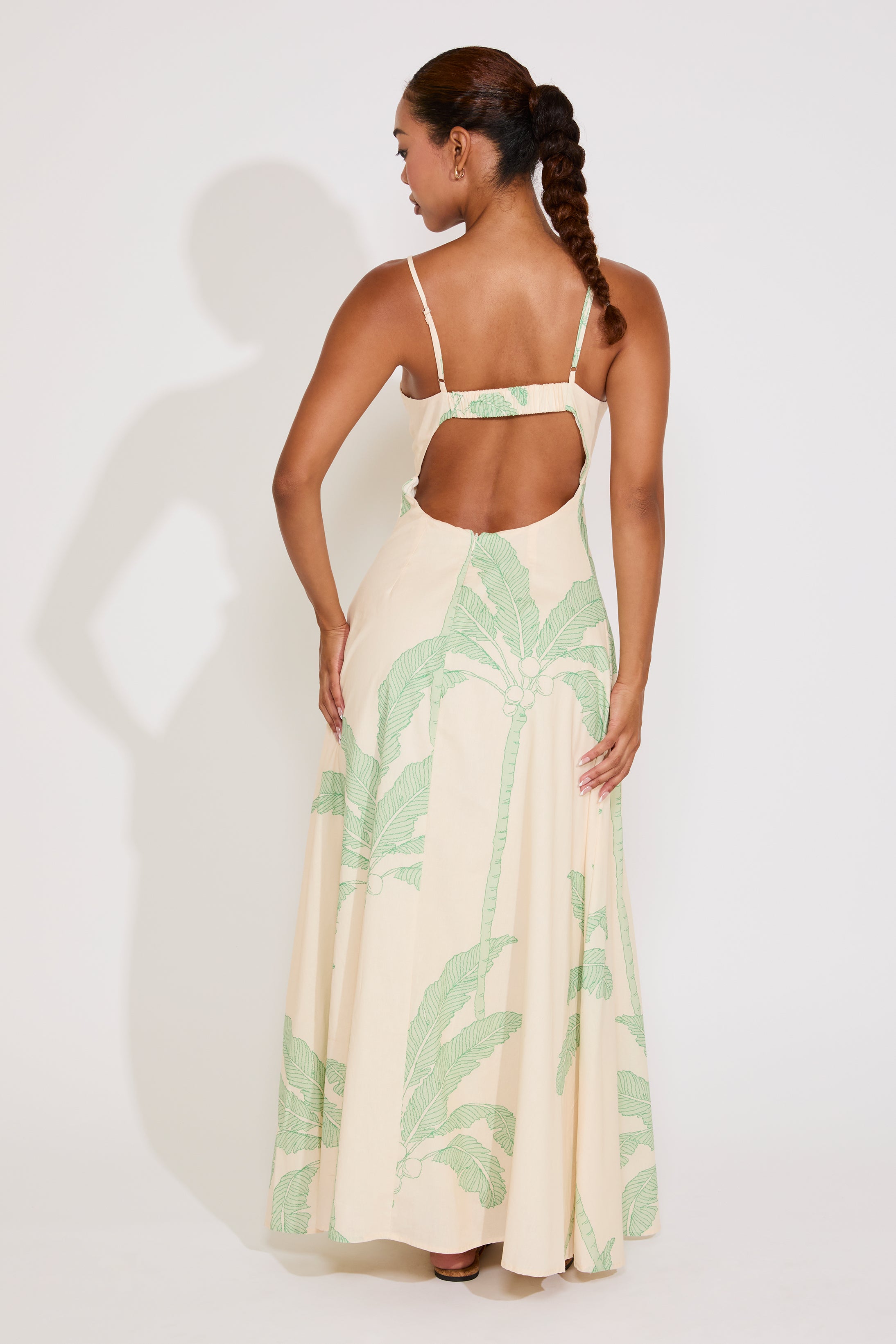 Woman wearing a beige dress with green leaf pattern on a white background