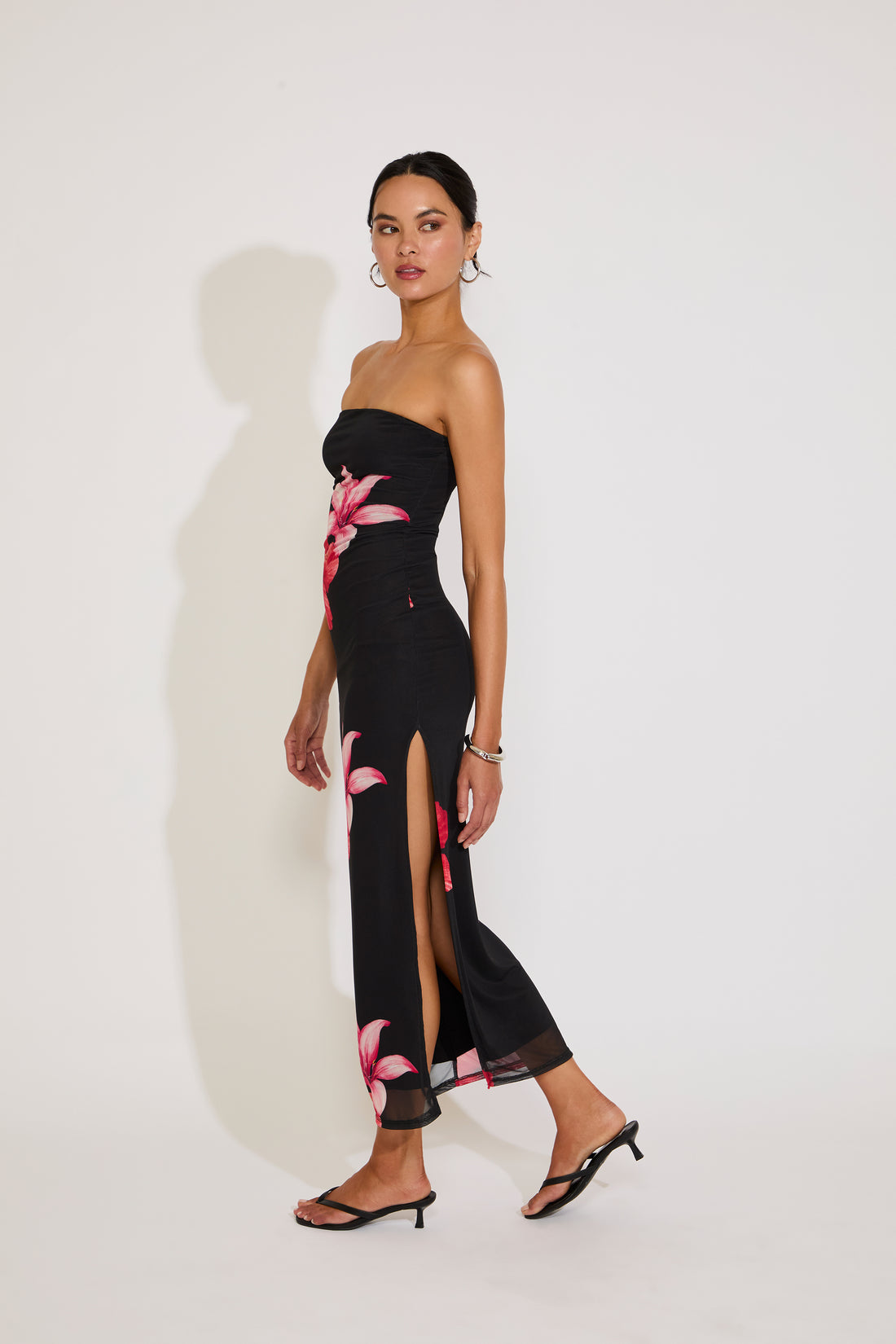 Woman wearing a black strapless dress with floral patterns on a white background