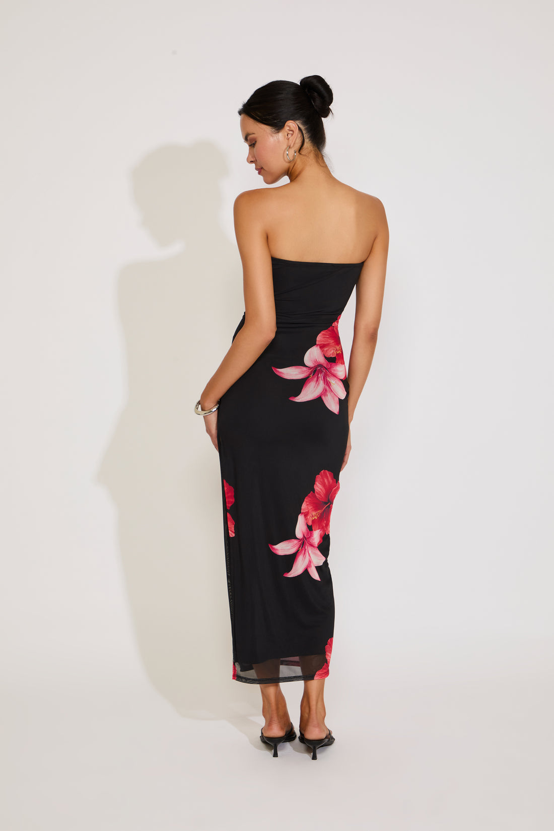 Woman wearing a black strapless dress with floral patterns on a white background