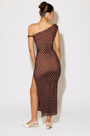 Woman wearing a brown one-shoulder dress with white polka dots on a white background