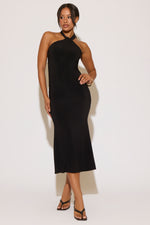 Woman wearing a black halter neck dress against a white background
