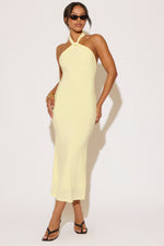 Woman wearing a light yellow halter neck dress on a white background