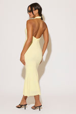 Woman wearing a light yellow dress with an open back on a white background