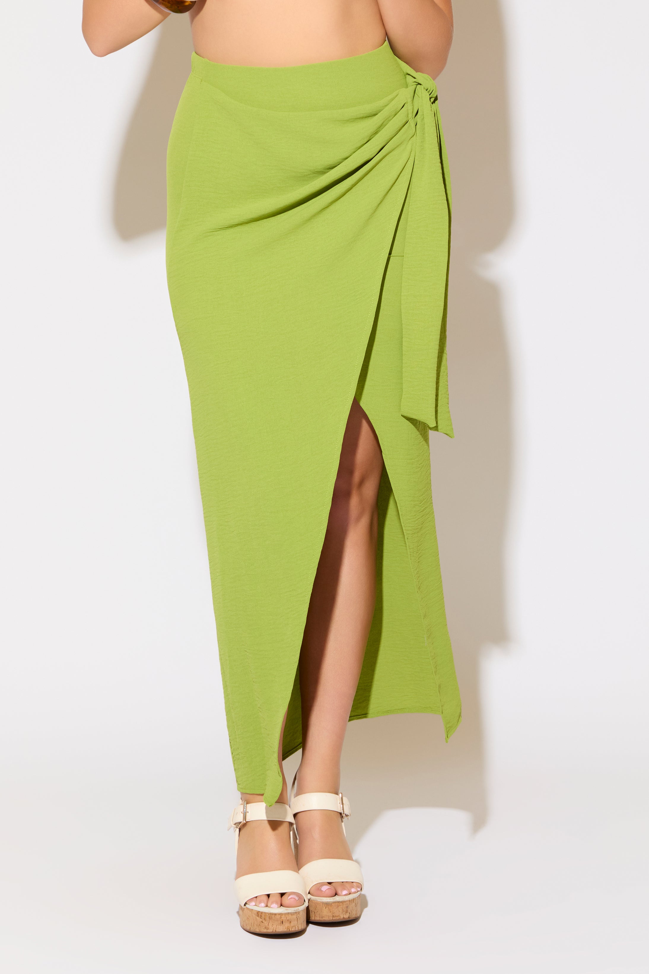 Model is wearing a moss green tie wrap overlay maxi skirt on a white background.