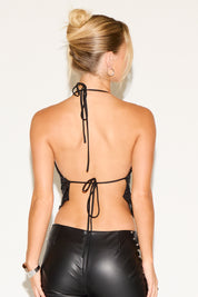 Woman wearing a black strappy top and black leather pants against a white background