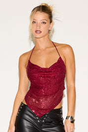 Woman wearing a red sequin top and black leather pants on a white background