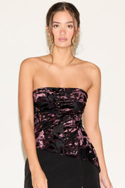Woman wearing a strapless top with black and pink floral pattern against a white background