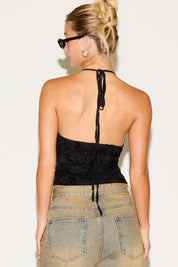 Person wearing a black strapless top and denim pants against a plain background