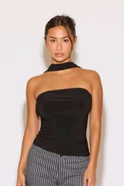 Woman wearing a black strapless top and striped pants against a white background