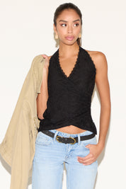 Model holding beige denim jacket wearing a black lace halter top