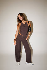 Woman wearing a brown pinstripe jumpsuit against a plain background