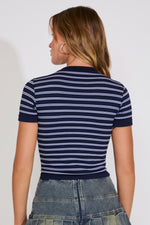 Person wearing a navy and white striped shirt with a plain background