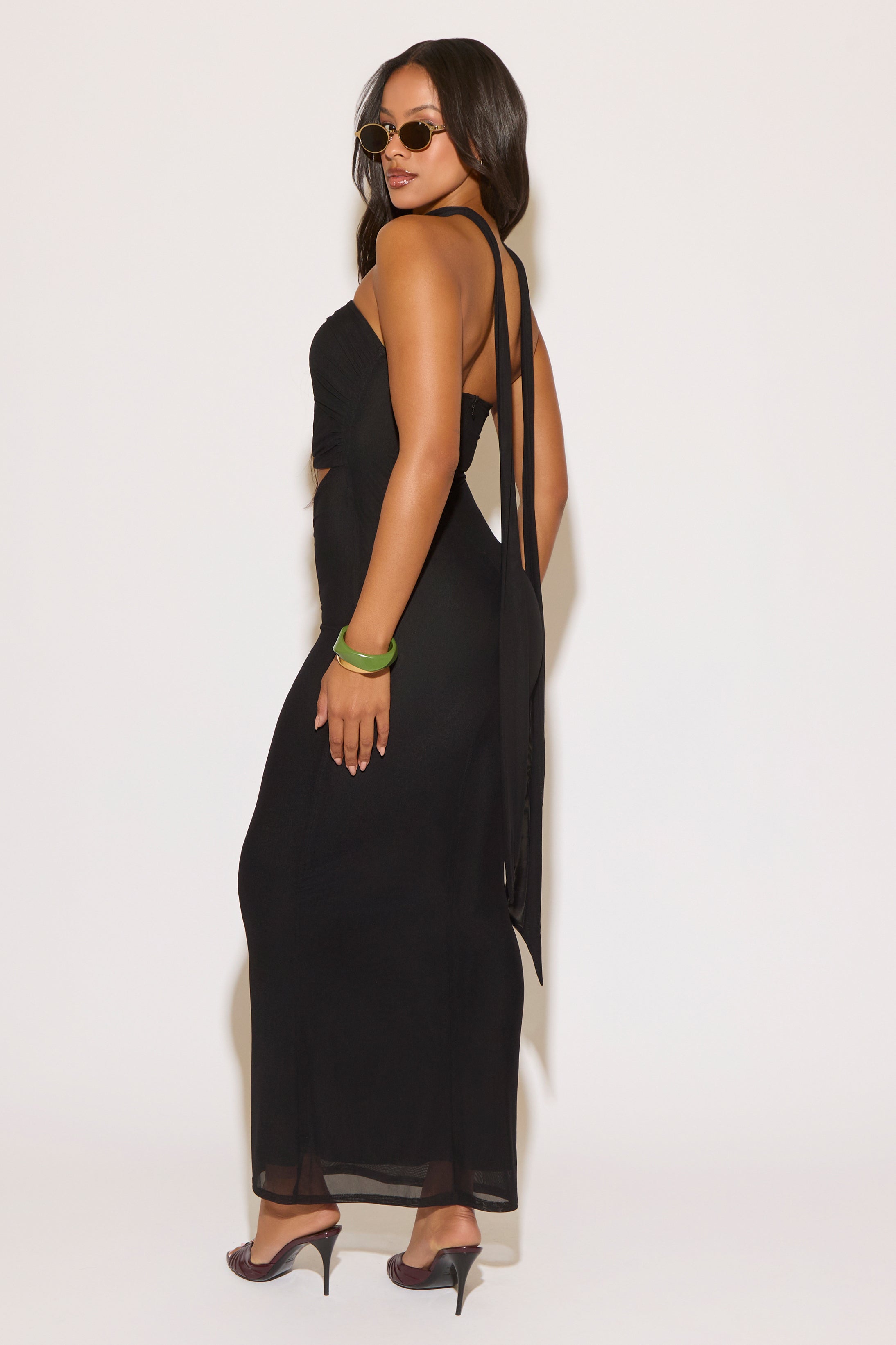 Woman wearing a black dress with cut-out sides against a white background