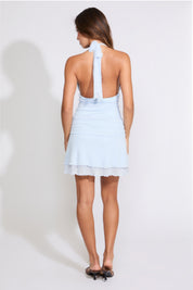 Model is wearing a blue TIE NECK RUCHED WAIST LAYERED MINI DRESS with brown heels on a white background.