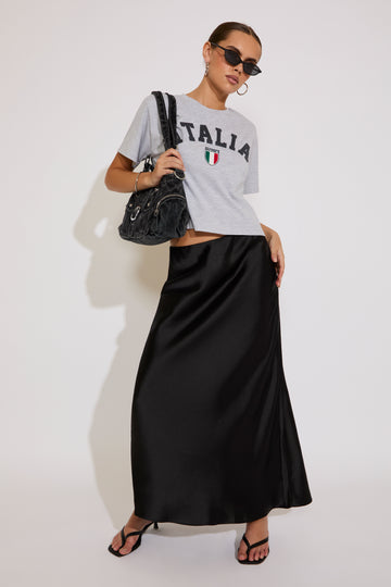 Woman wearing a graphic t-shirt and black skirt with sunglasses on a white background