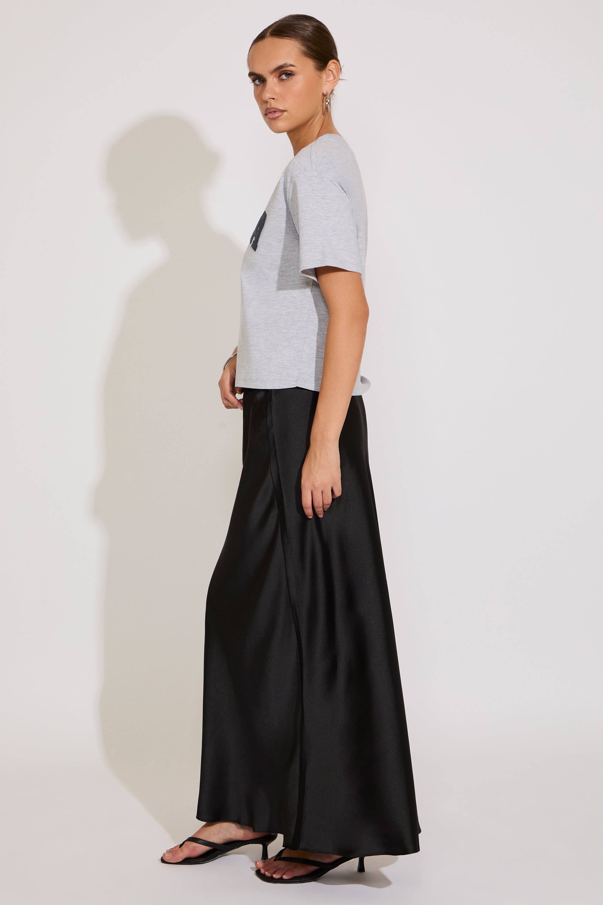 Woman wearing a gray t-shirt and black wide-leg pants on a white background