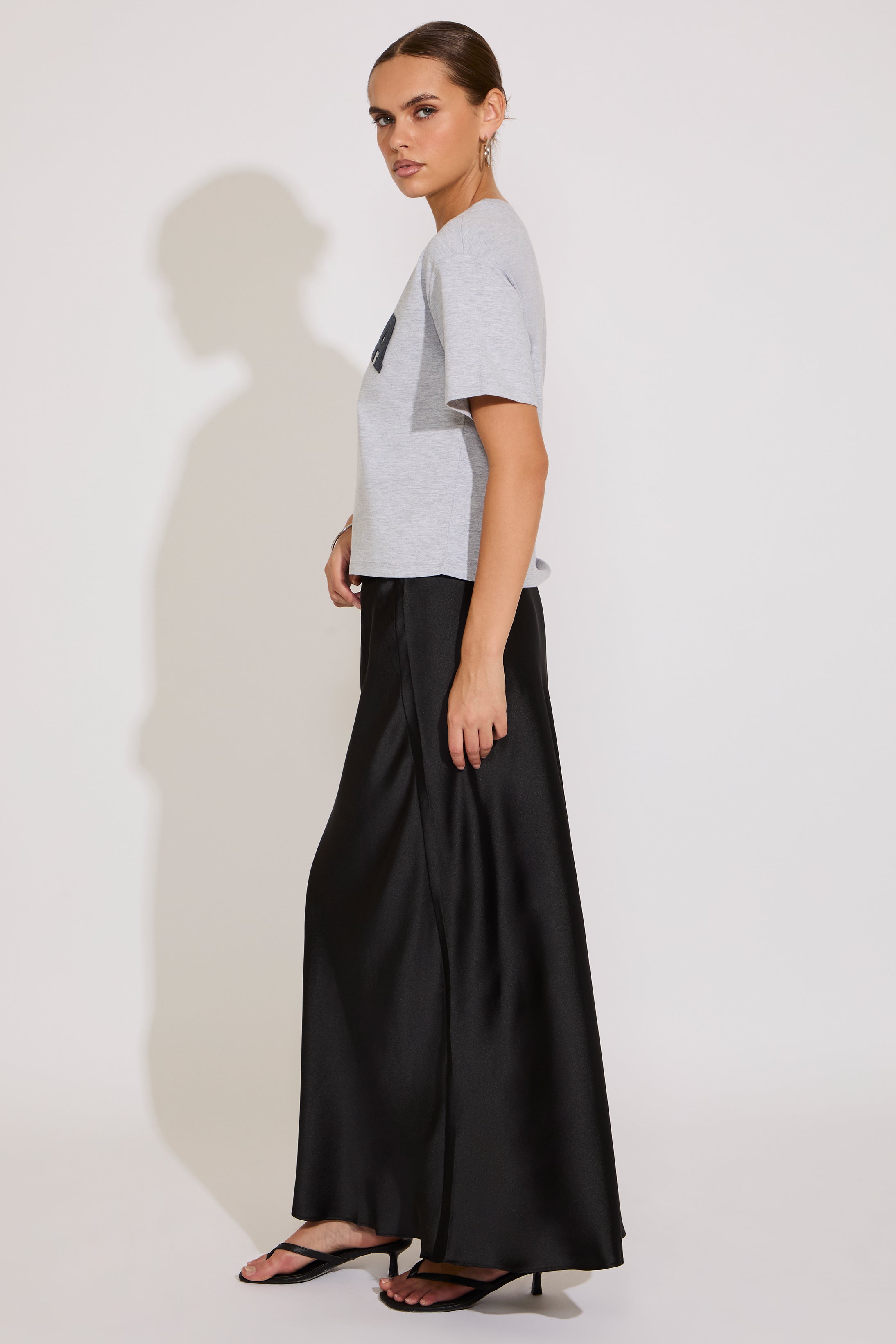 Woman wearing a gray t-shirt and black wide-leg pants on a white background
