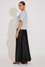 Woman wearing a light gray top and black wide-leg pants on a white background
