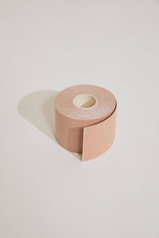 Roll of beige body tape on a light gray background