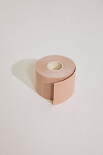 Roll of beige body tape on a light gray background