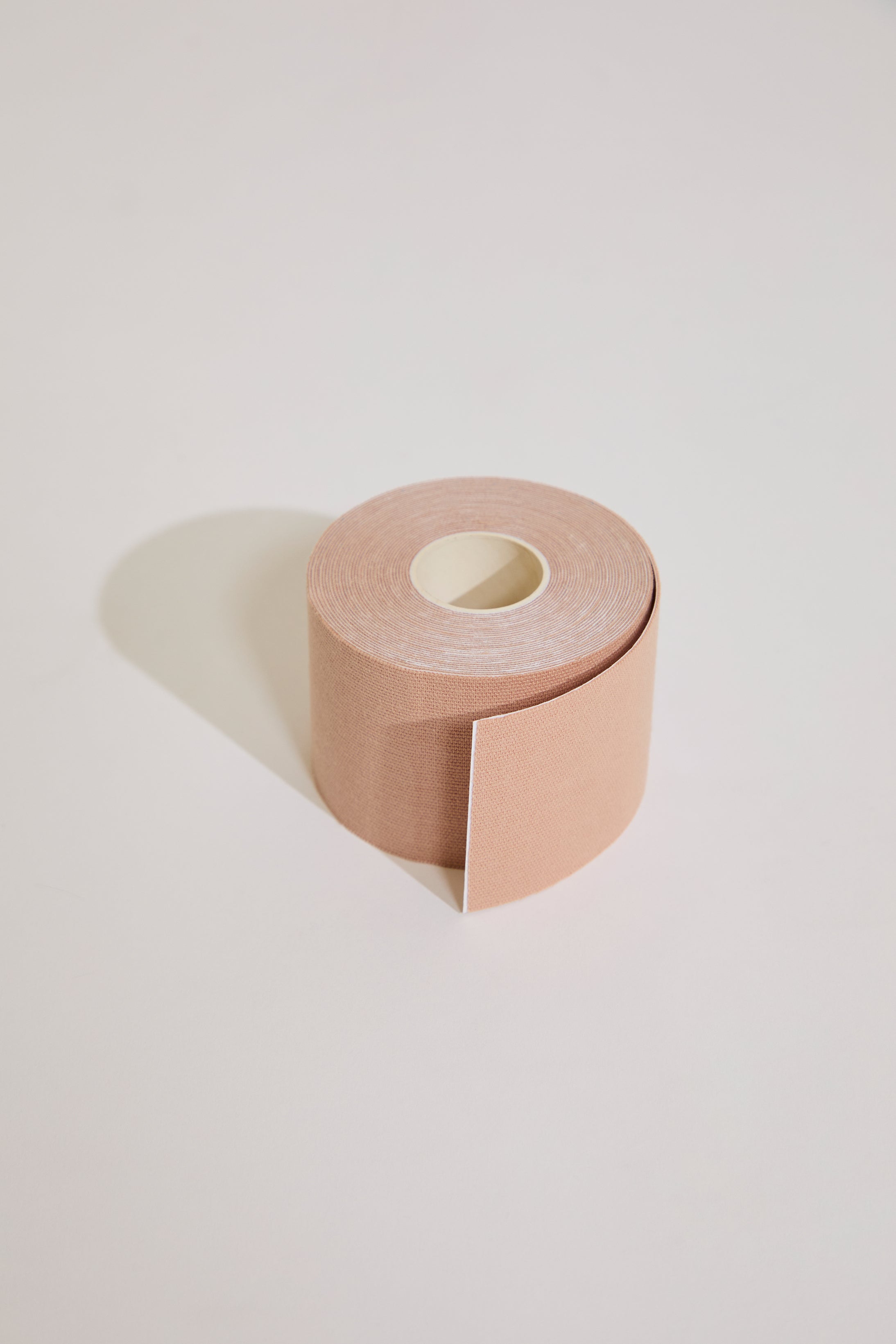 Roll of beige body tape on a light gray background