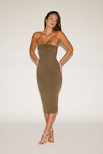 Woman wearing a strapless olive green dress on a white background