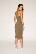 Woman wearing a strapless olive green dress against a white background