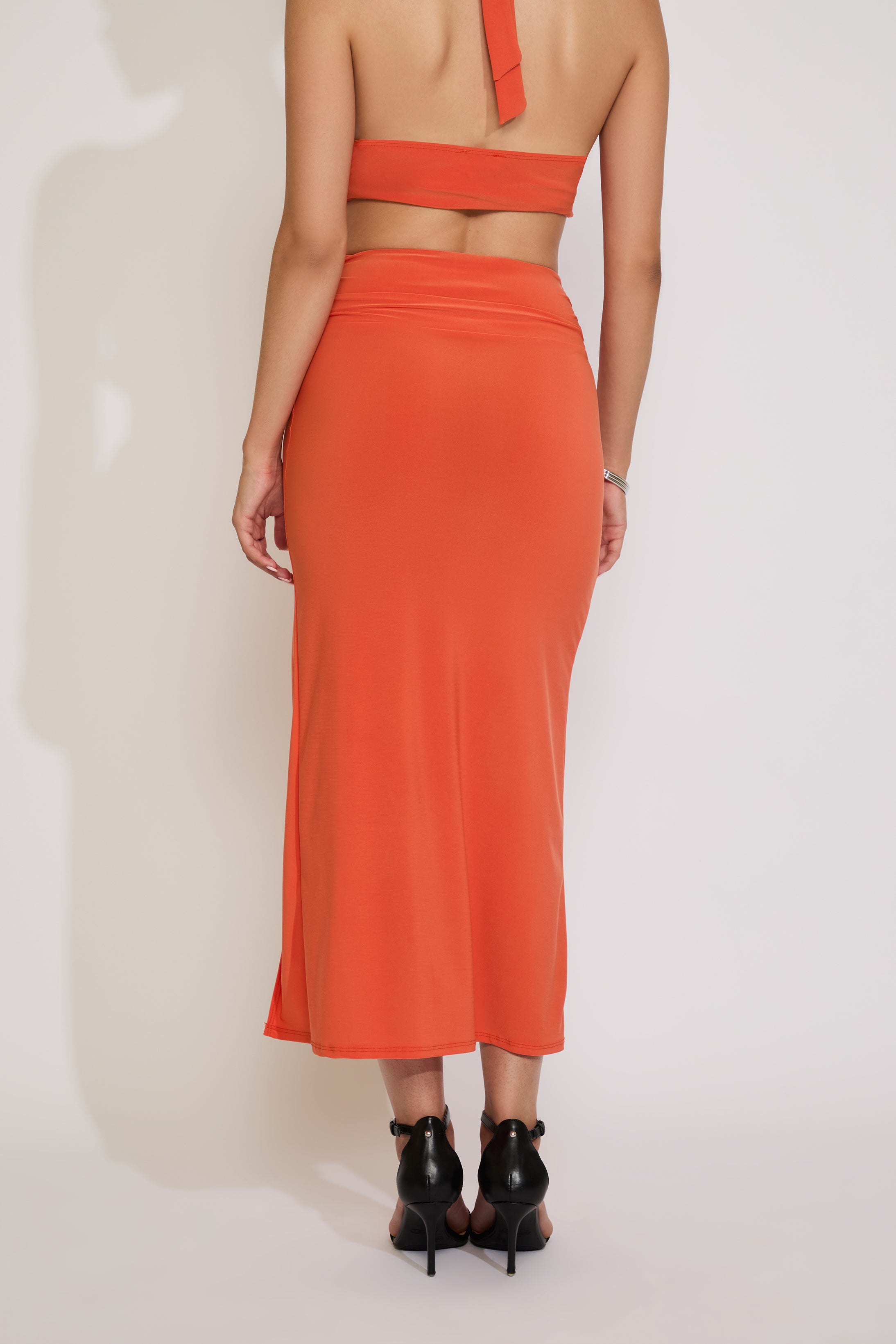 Person wearing an orange two-piece outfit with a plain background