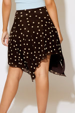 Black polka dot skirt worn by a person on a plain background