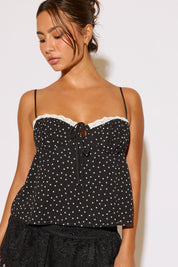 Woman wearing a black polka dot top against a white background