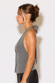 Woman wearing a gray sleeveless top with a polka dot pattern against a white background