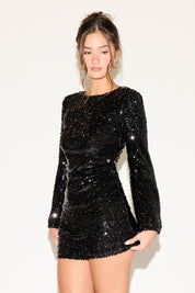 Woman wearing a black sequin dress against a white background