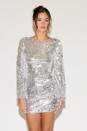 Woman wearing a silver sequin dress against a white background