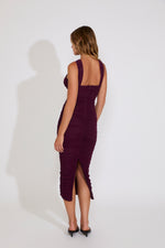 Woman wearing a purple dress with a slit on a white background