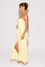 Woman wearing a strapless yellow dress with a slit on a white background
