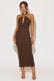 Woman wearing a brown halter neck dress against a white background