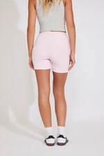 Person wearing light pink biker shorts on a plain background