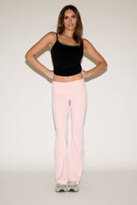Woman wearing a black tank top and pink pants on a white background