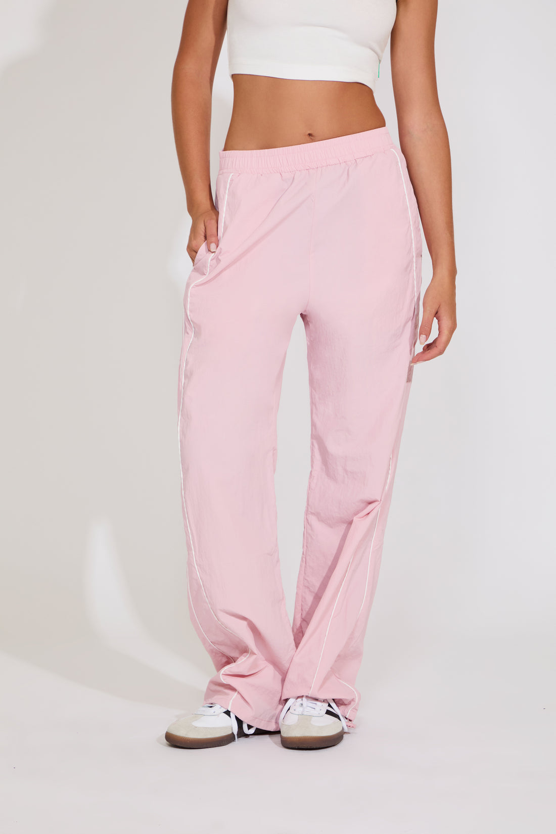 Woman wearing a white crop top with a star design and light blue pants on a plain background