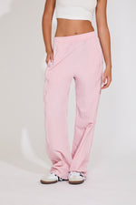 Person wearing pink sweatpants and a white top on a light background