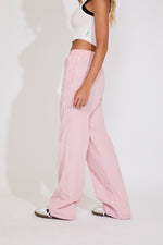 Person wearing pink pants and a white top on a plain background