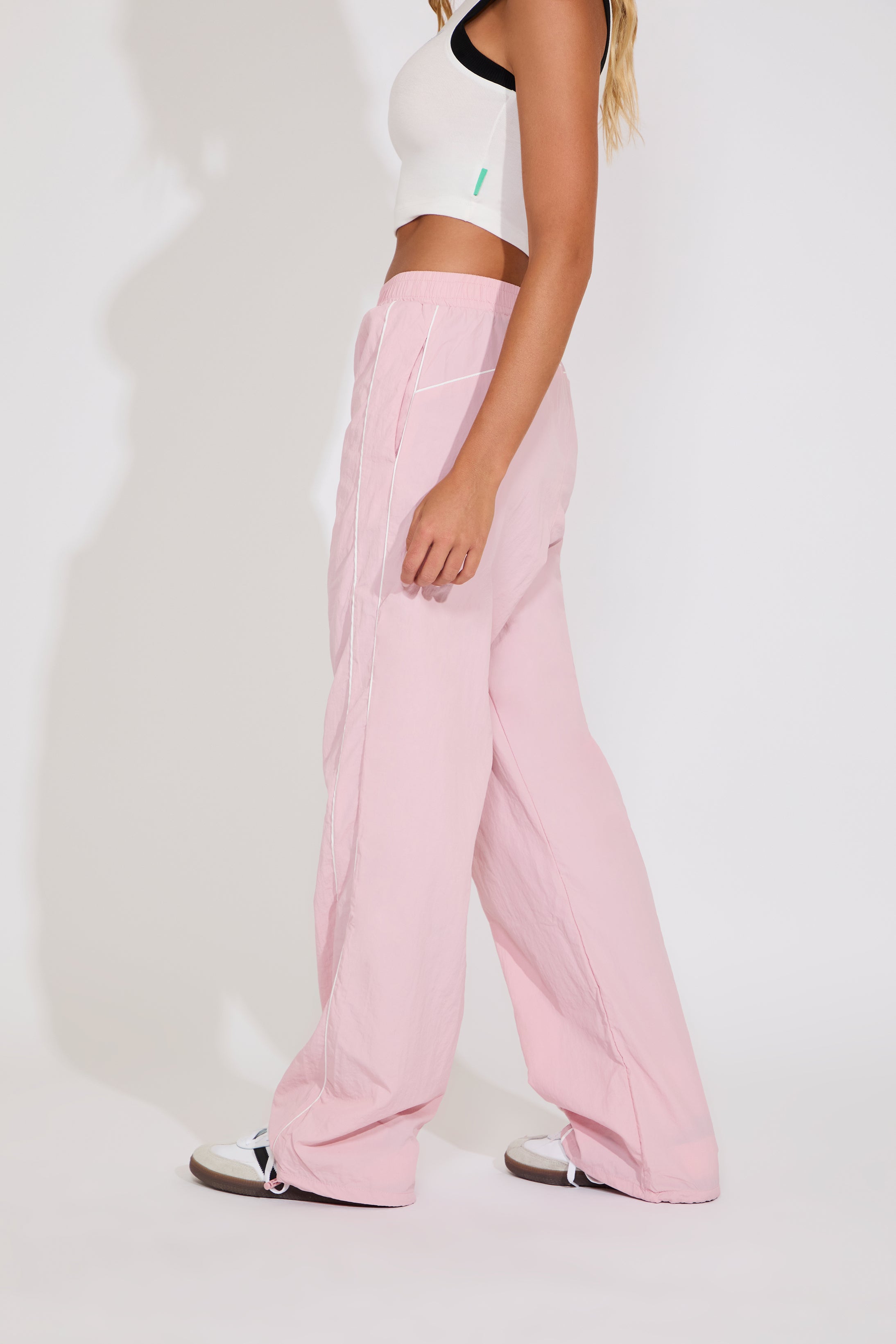 Person wearing pink pants and a white top on a plain background