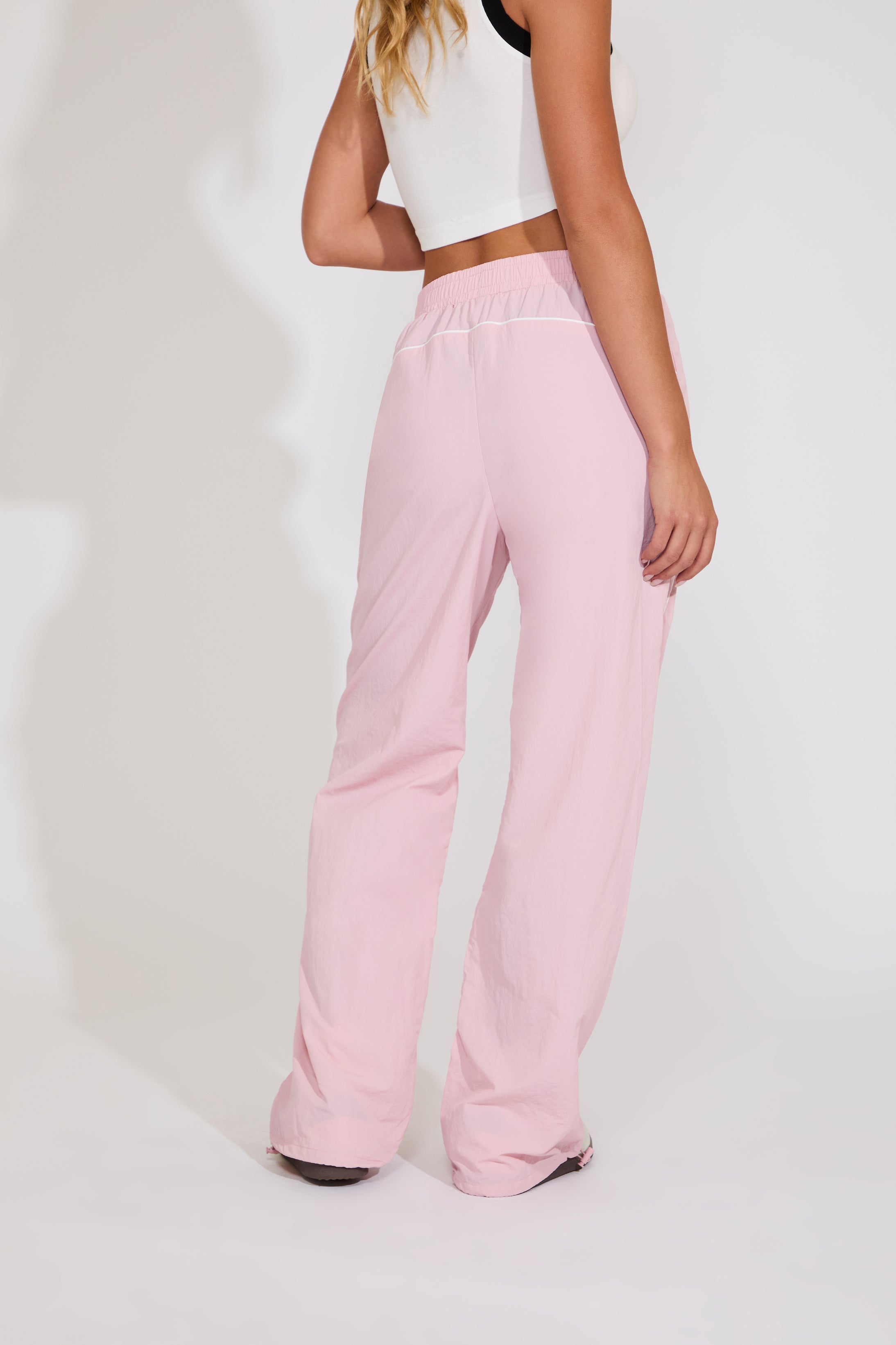 Person wearing pink pants and a white top on a plain background