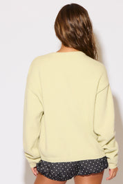 Person wearing a light green sweatshirt and black shorts with white polka dots on a plain background