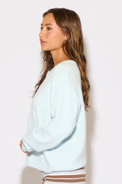 Woman wearing a light blue sweatshirt against a plain background
